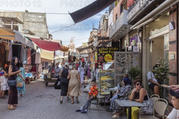Lively street full of people with street cafés and shops, relaxed hustle and bustle