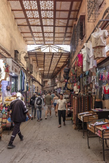 Covered market street with lots of people and colorful clothing stores
