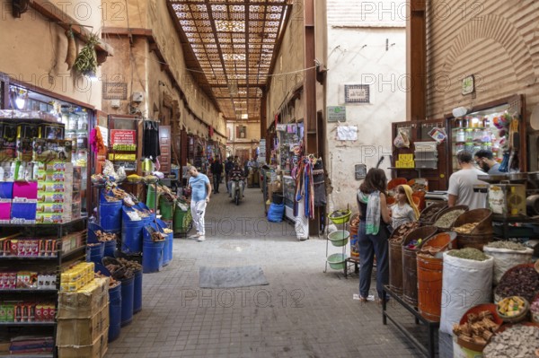 Lively, covered market street with various stalls and people shopping