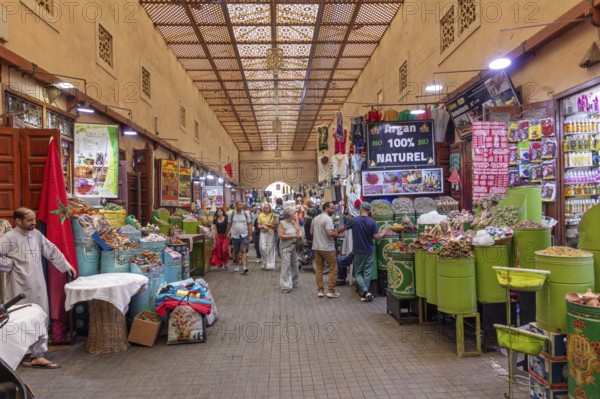 Lively market with numerous stalls full of fruit and goods under a decorative roof