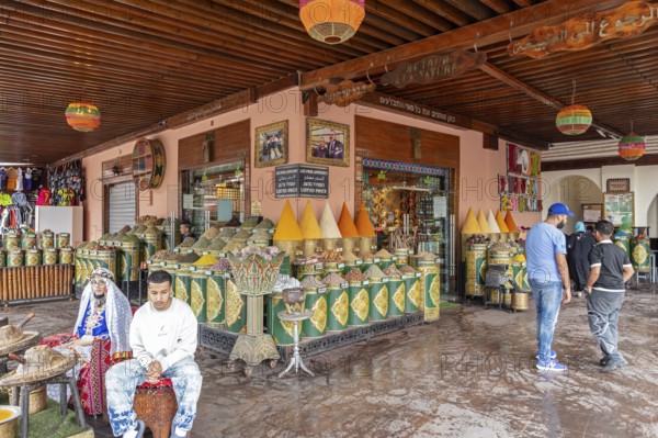 Market square with large, decorative vessels full of spices and people, inspired by Arabic