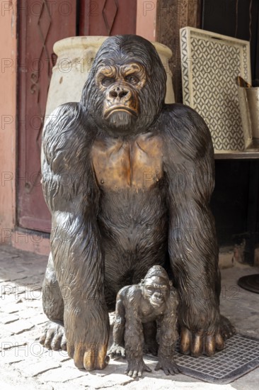 A large statue of a gorilla monkey with a young in a busy environment