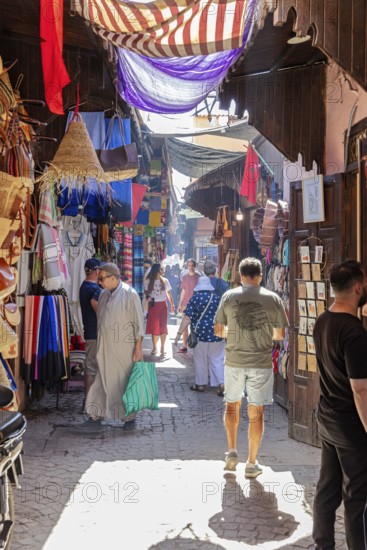 Colourful market with fabrics and lamps, full of people and lively hustle and bustle