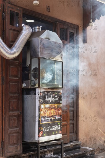 A grill outside a door that emits smoke, probably for preparing street food at night