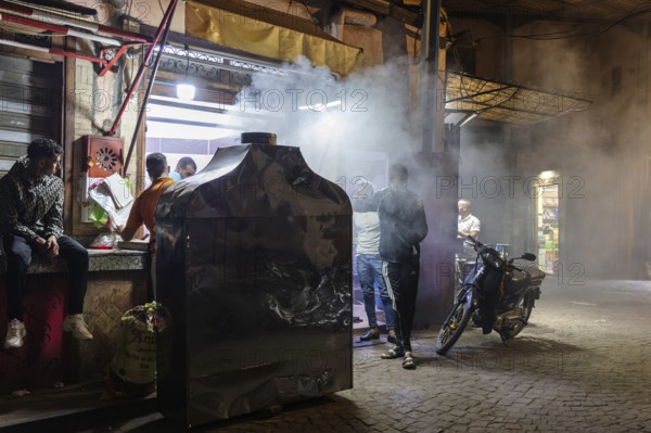 A busy street scene at night with people and smoke in an urban area
