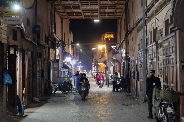 Night view of a busy alley with people, shops and alleyway lights in an old town
