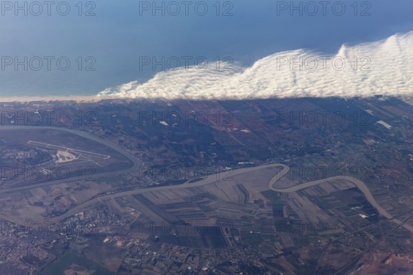 Aerial view of a coastal landscape with waves, agricultural fields and an airport