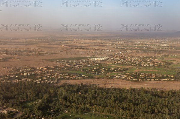 Aerial view of a vast landscape with green fields, trees and mountains in the background