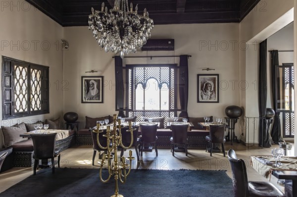 Elegant restaurant dining room with chandeliers, black and white paintings and large windows