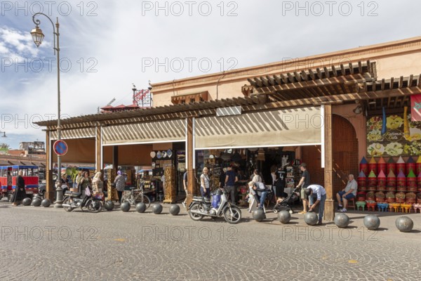 Lively market street with kiosks, traffic and people in sunny weather