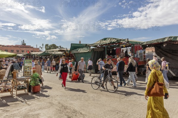Lively market with people, bikes and stalls under a blue sky