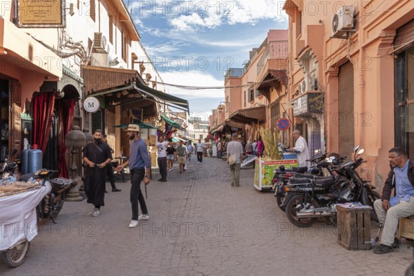 People stroll along a street with various shops