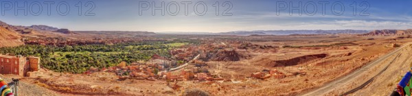 Wide desert landscape with oasis and village under a clear sky
