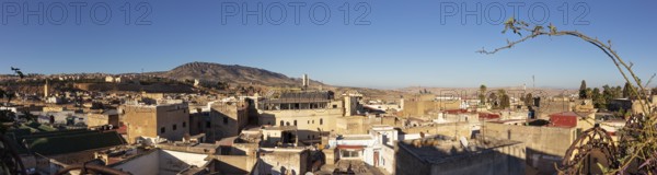 Extensive urban landscape with hills in the background and clear sky