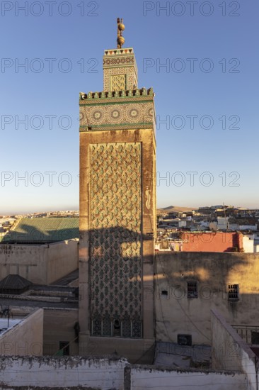 Decorated minaret over the cityscape in the light of the setting sun