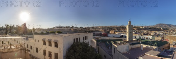 Panoramic view of an urban landscape with minaret and hilly background