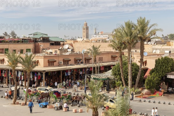 Lively market scene with palm trees and a minaret in traditional surroundings when the sun is shining