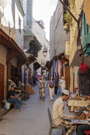 A busy, narrow street full of market stalls and people wearing traditional clothes