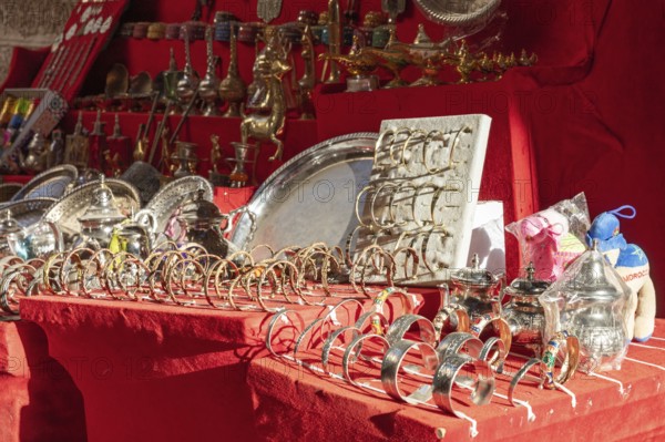 A market stall full of shiny silver and jewelry on red fabric