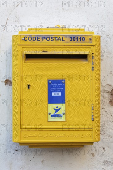 Yellow letterbox on a wall with Arabic and French letters