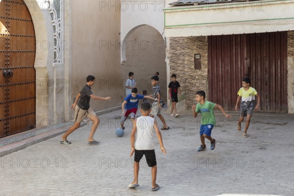 Children play soccer in a narrow alley. Carefree summer atmosphere