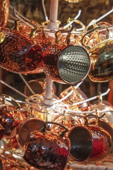 A collection of shiny copper cups and vessels presented at a stand
