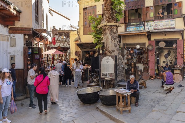 Bustling bazaar with people and traditional craft stalls along a street