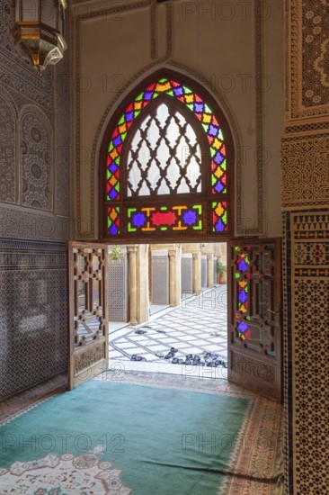 A sumptuous interior with a colorful stained glass window that throws light into the room in traditional patterns