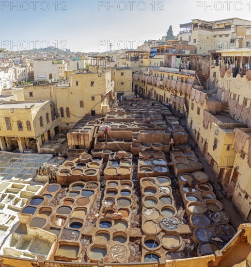A panoramic view of a traditional old town tannery with many basins and weathered buildings in warm shades of yellow
