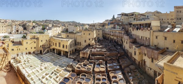 A wide view of a traditional Moroccan tannery in the middle of the lively cityscape with buildings