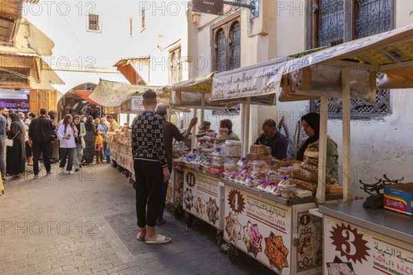 Market scene with people and various food stalls in an old town street