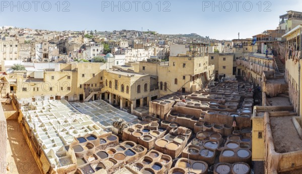 Traditional tannery in Fez under clear skies with numerous leather troughs