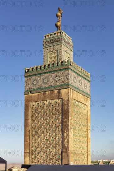 Close-up view of a richly decorated minaret against a clear sky