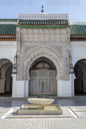 A richly decorated Islamic building with a central well, surrounded by mosaics and Islamic architectural elements