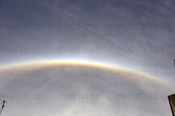 Glowing semicircular halo on cloudy sky