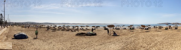 Extensive sandy beach with umbrellas on a clear blue sky