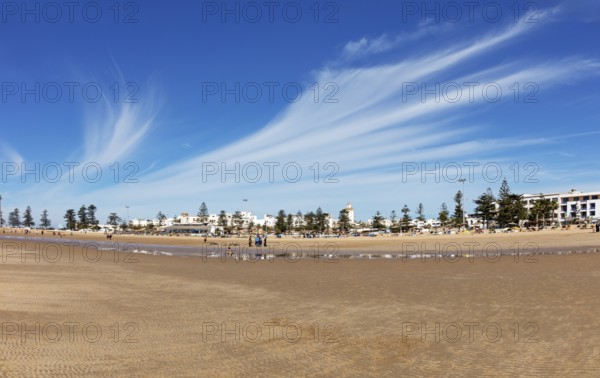 Wide sandy beach with townhouses and dramatic cloudy skies
