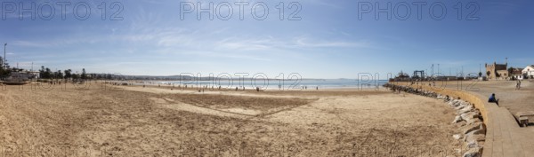 Panoramic view of a wide sandy beach next to the sea under clear skies