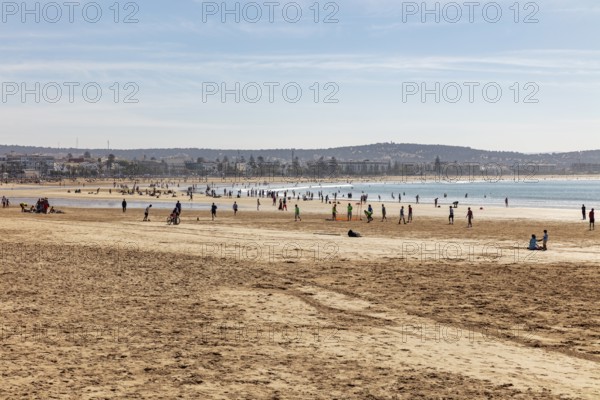 People frolic on the sandy beach with views of the vast sea and the blue sky
