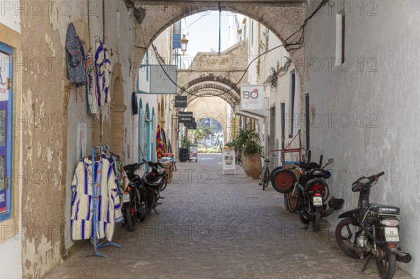 Narrow alley with arches, hanging clothes and parked bikes during the day