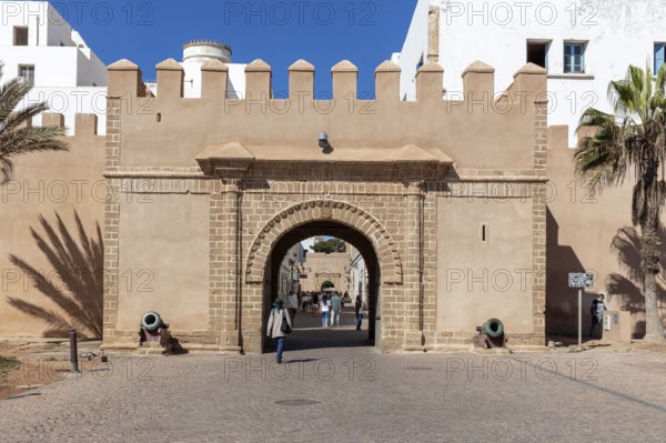 Historic city gate with archway and people, illuminated by daylight