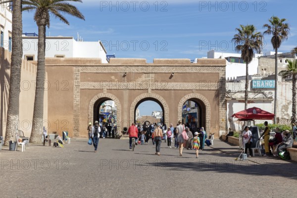 Busy street with access gate and palm trees under a clear sky