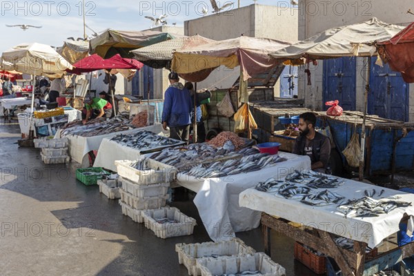 Market scene with fish stalls and vendors, colorful umbrellas and people in a peaceful atmosphere