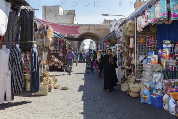 Bustling market street with numerous stalls and archways under the sun