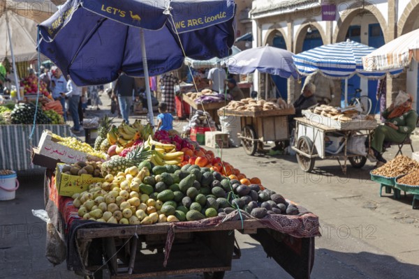Fertile market stand under umbrellas with a variety of fruits and customers