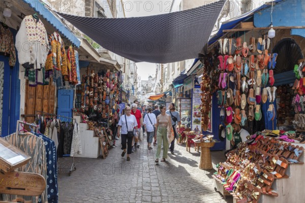 Lively market in a narrow alley with lots of colorful products and buyers