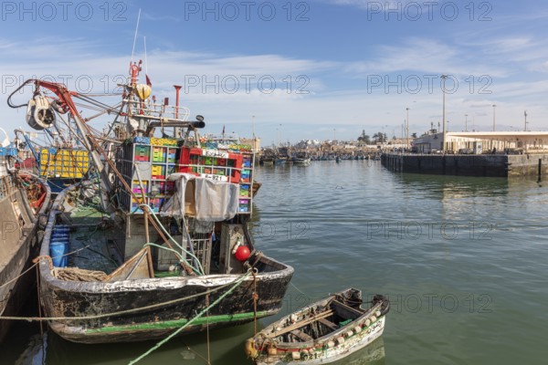 A fishing boat loaded with colorful boxes in the harbor, still water and blue skies
