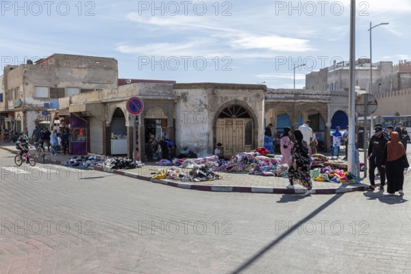 Lively street scene with market stalls and people in a sunny city