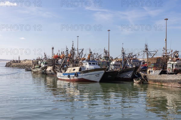Row of fishing boats in the calm waters of the harbor, clear skies and seagulls in the distance