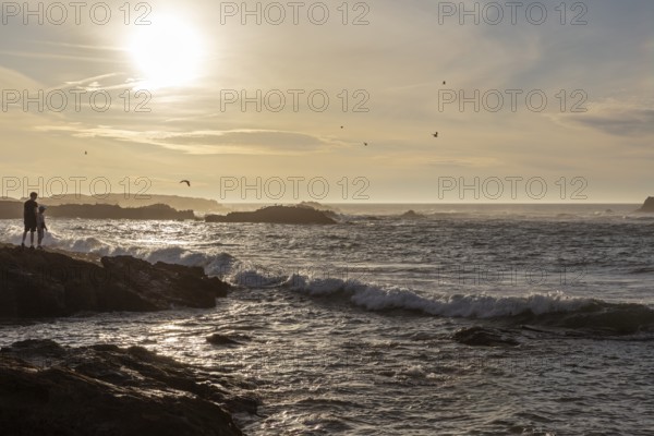 Romantic coastal scene with sunset and silhouettes on the seashore